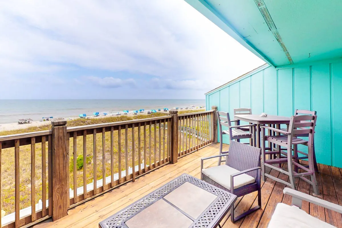 A stunning exterior deck scene with outdoor seating, wooden railing, and panoramic ocean views. The setting invites guests to relax, socialize, or dine al fresco while soaking in the sights and sounds of the Atlantic.
